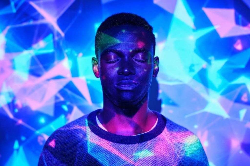 Peaceful black man standing in colorful neon projection
