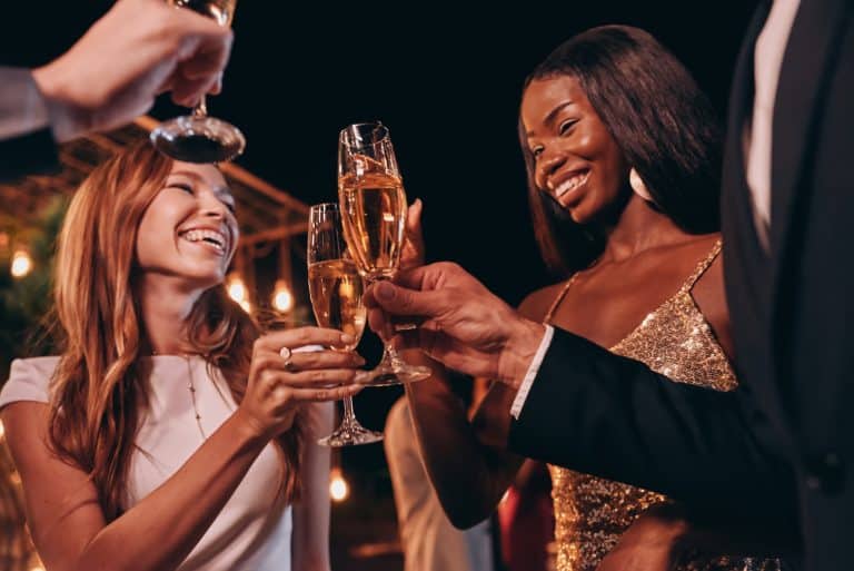 Grupo de personas en ropa formal brindando con champán y sonriendo