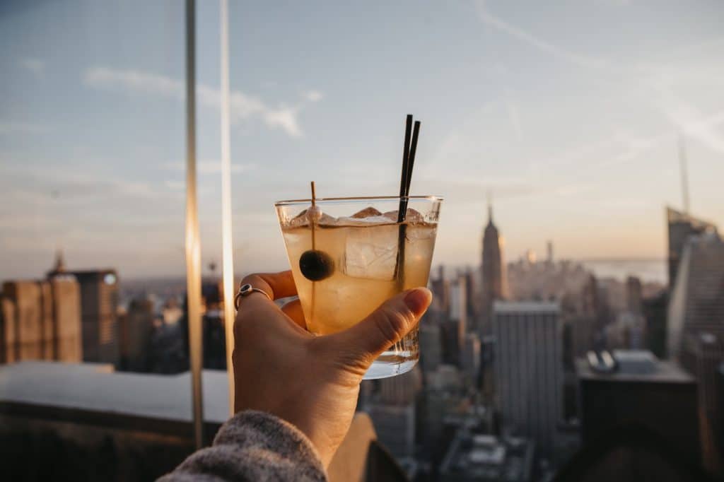 Estados Unidos, Nueva York, Ciudad de Nueva York, mano con copa de cóctel al amanecer.