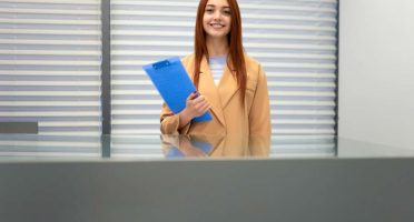 Secretary with clipboard in hands stands at the office reception