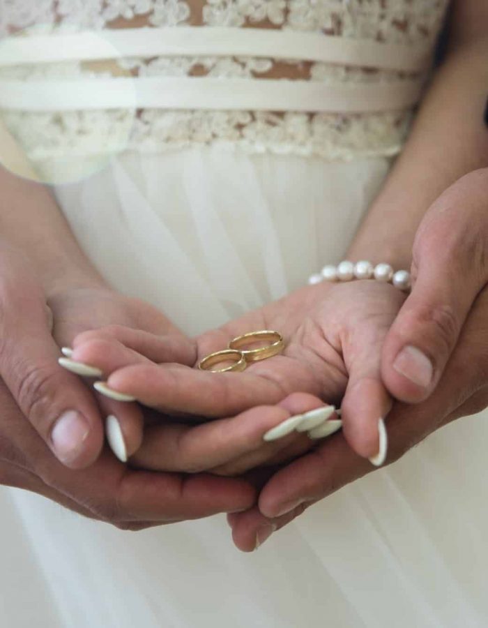 Dos anillos de boda dorados en las palmas de la novia y el novio. Anillo de bodas